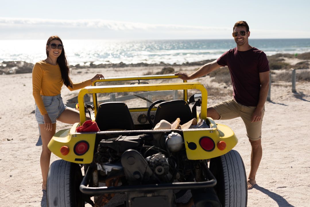 Portrait of happy caucasian couple standing by beach buggy on sunny beach by the sea - Free Images, Stock Photos and Pictures on Pikwizard.com