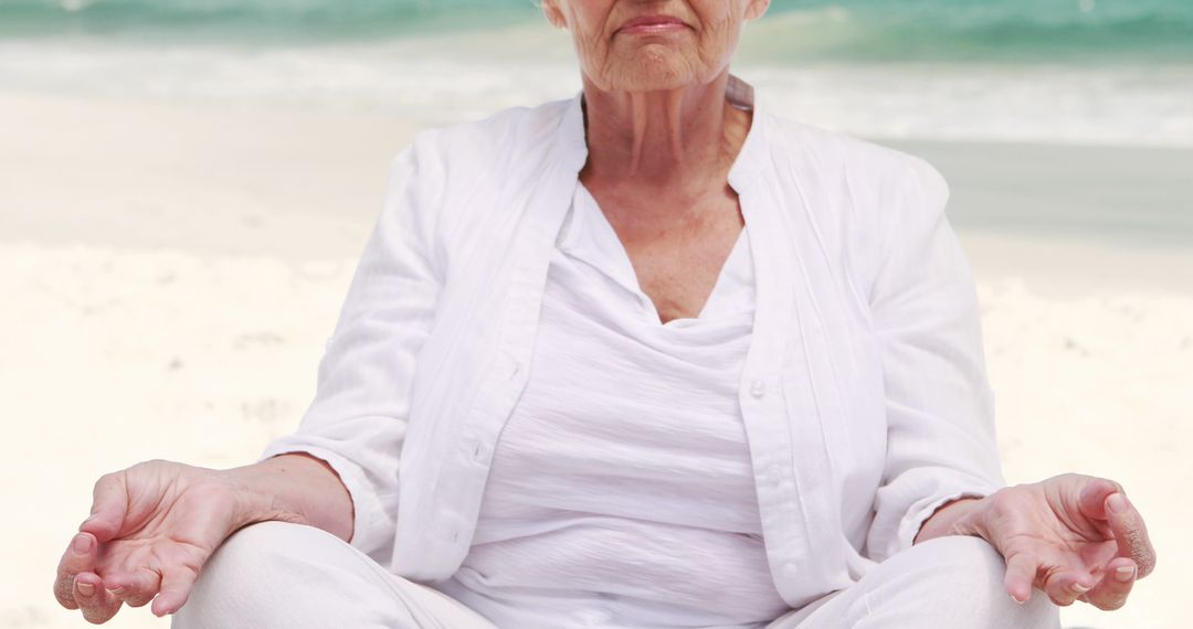 Senior Woman Meditating on Beach in Serene White Outfit - Free Images, Stock Photos and Pictures on Pikwizard.com