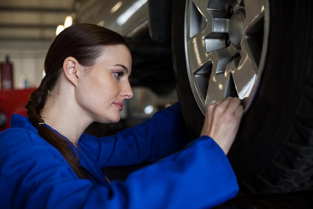Female mechanic examining a car wheel - Free Images, Stock Photos and Pictures on Pikwizard.com