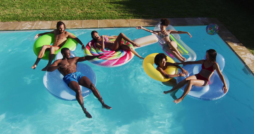 Group of Friends Floating on Colorful Pool Floats Laughing and Relaxing in Backyard Summer