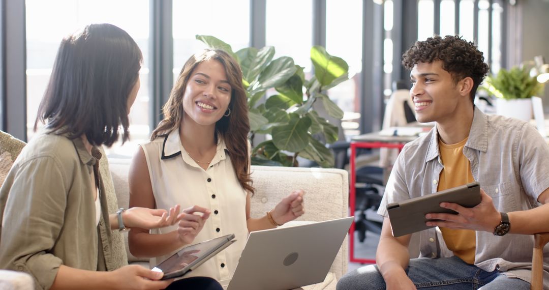 Diverse Team Collaboration in Modern Office Lounge with Laptops and Tablets