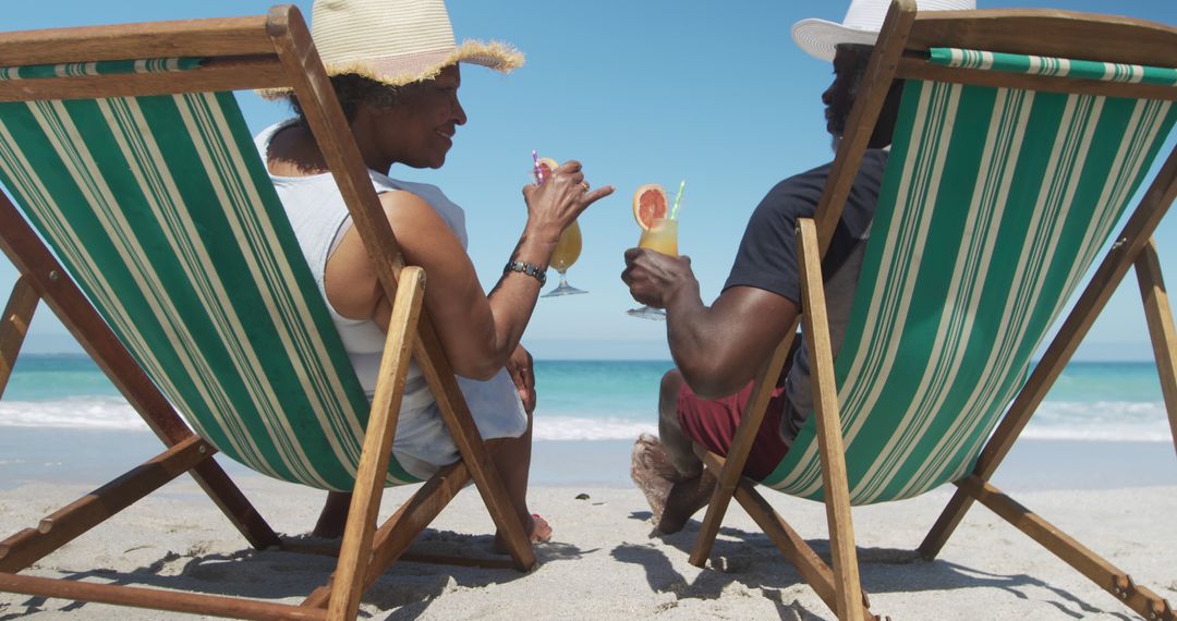 Couple Enjoying Refreshing Drinks on Sunny Beach Relaxing on Deck Chairs - Free Images, Stock Photos and Pictures on Pikwizard.com