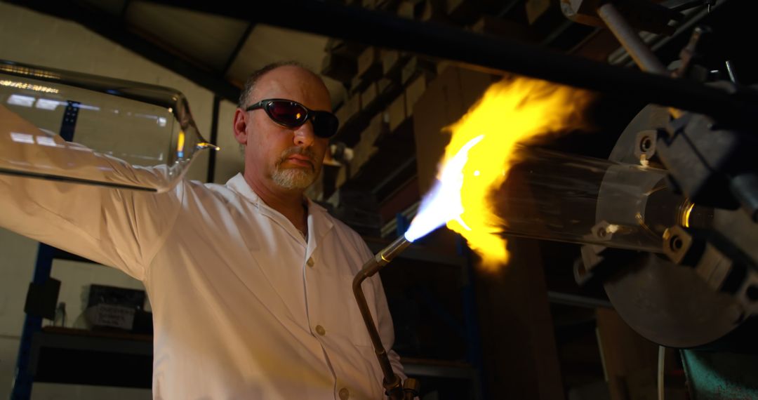 Skilled Artisan Using Torch to Shape Glass in Factory Workshop