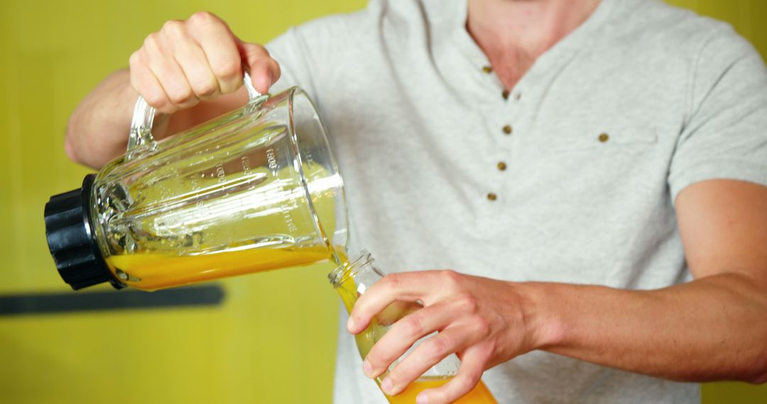 Man Pouring Freshly Blended Orange Juice into Bottle - Free Images, Stock Photos and Pictures on Pikwizard.com