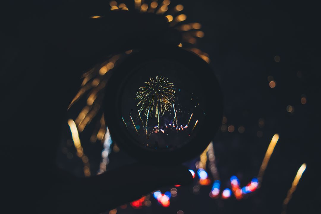 Fireworks Reflected Through Circular Lens Held in Hand