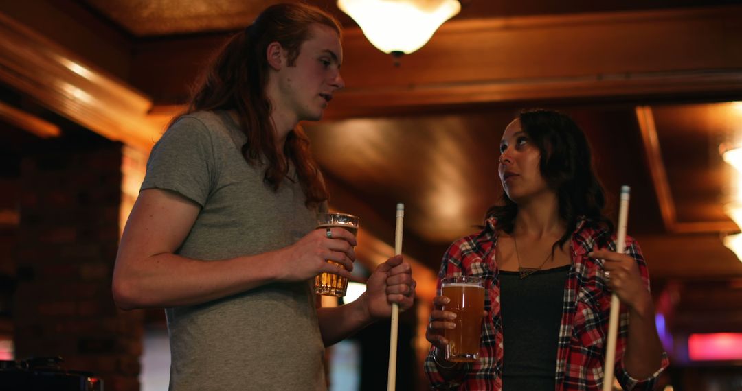 Friends Socializing with Drinks and Billiard Cues in Relaxed Bar Environment