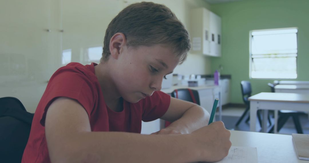 Boy Writing and Concentrating at Classroom Desk During Study Session