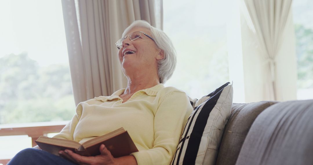 Elderly Woman Laughing While Reading Book at Home - Free Images, Stock Photos and Pictures on Pikwizard.com