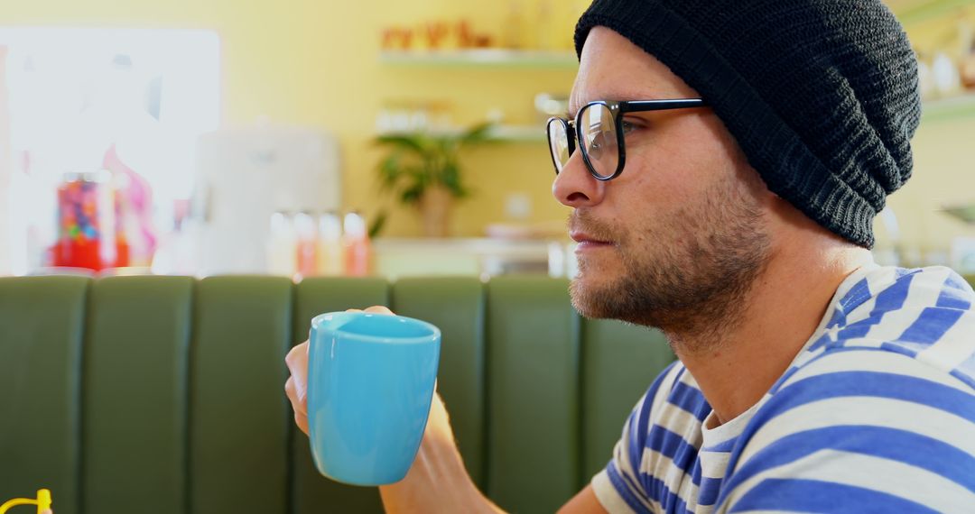 Young Man with Beanie Drinking Coffee at Café - Free Images, Stock Photos and Pictures on Pikwizard.com