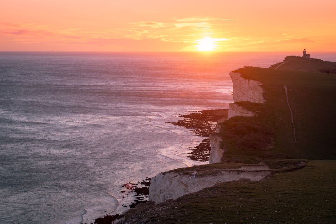 Scenic Coastal Cliff at Sunset with Lighthouse in Distance - Free Images, Stock Photos and Pictures on Pikwizard.com