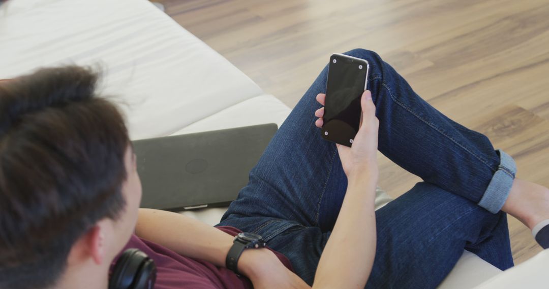 Young Man Relaxing on Sofa Using Smartphone at Home - Free Images, Stock Photos and Pictures on Pikwizard.com