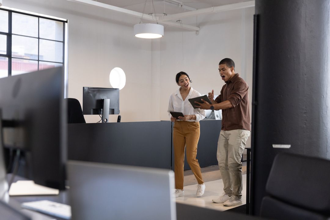 Workers Discussing Project Details on Tablets in Bright Modern Office