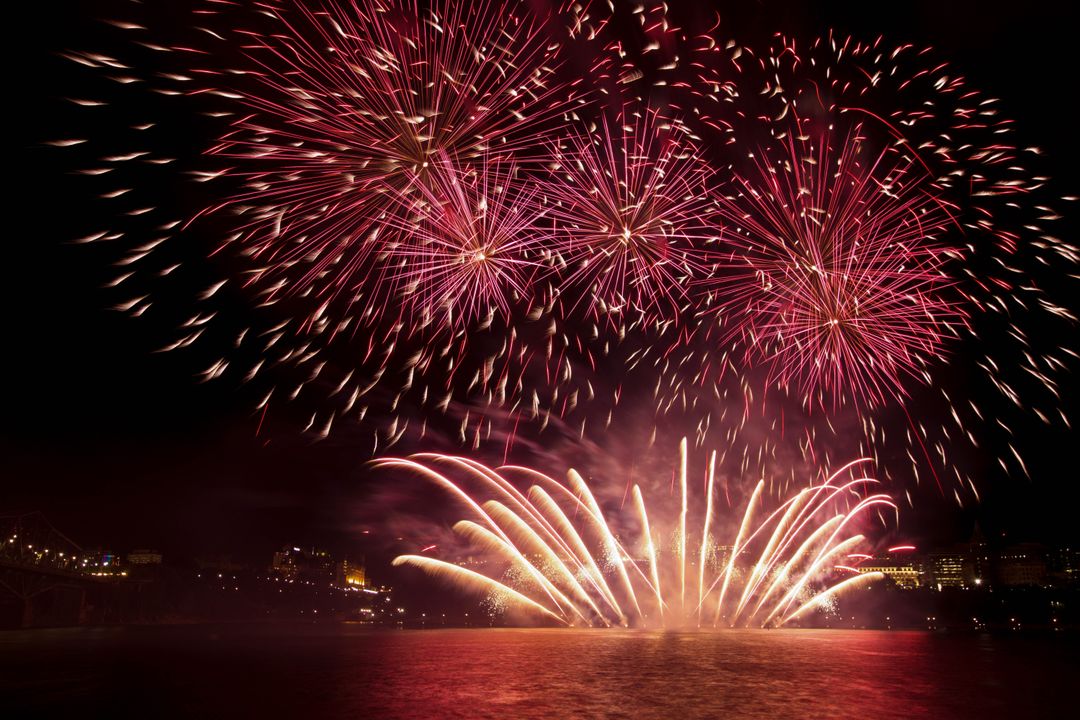Spectacular Red Fireworks Over River at Night