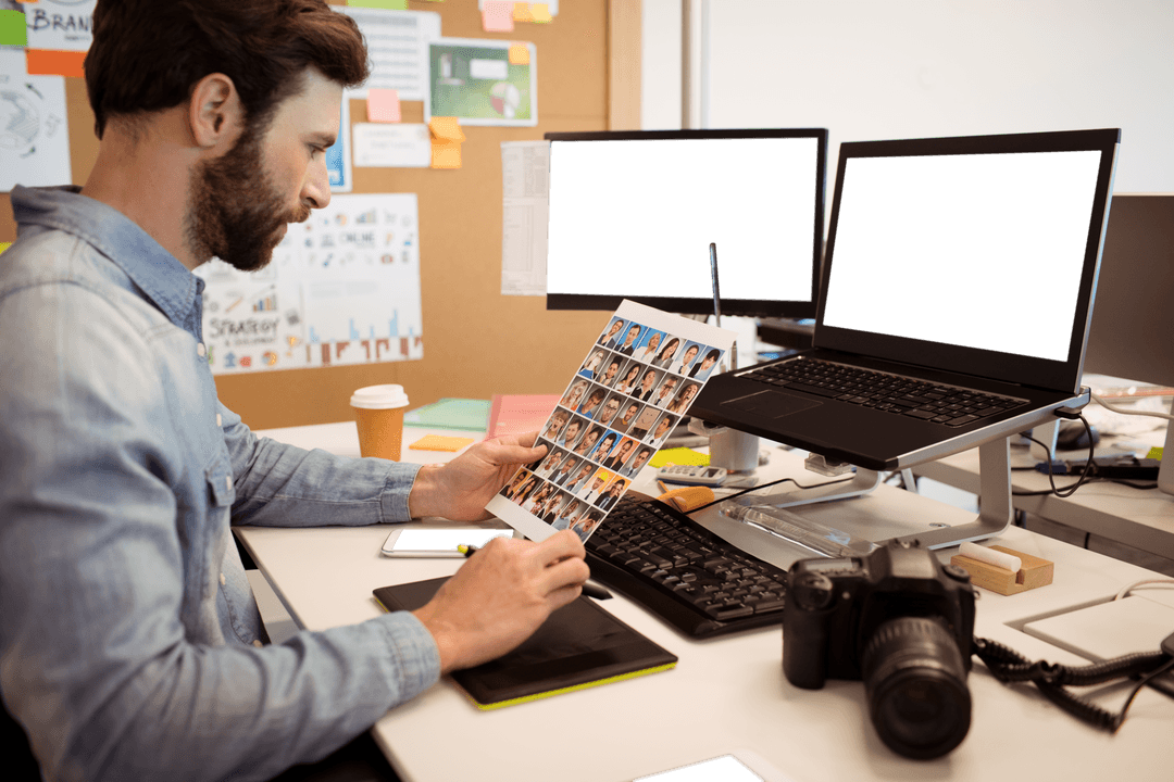 Creative Designer Viewing Transparent Photograph Sheet at Modern Workspace