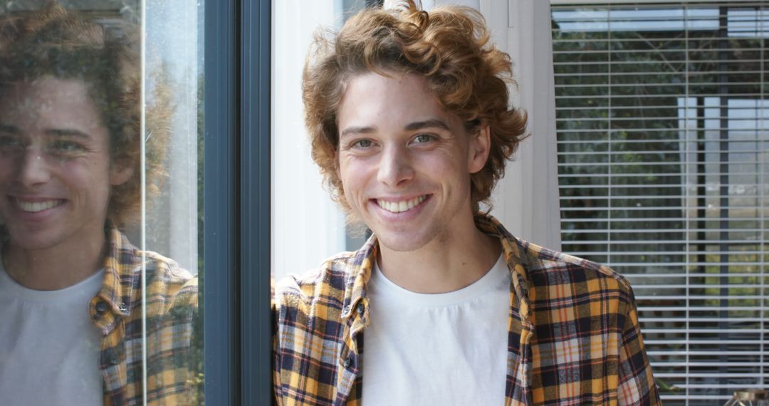 Young Man Smiling Near Window Wearing Yellow Plaid Shirt - Free Images, Stock Photos and Pictures on Pikwizard.com