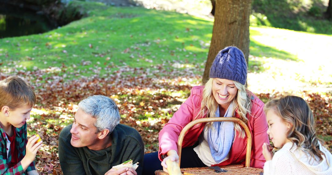 Family Enjoying Picnic Under Tree in Park During Autumn Day - Free Images, Stock Photos and Pictures on Pikwizard.com