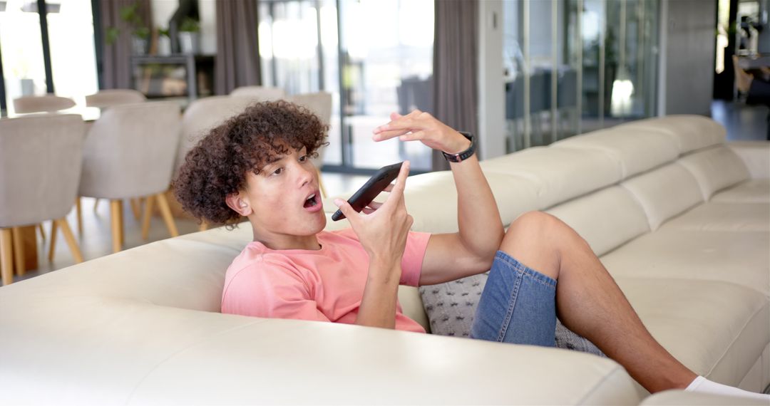 Young Man Using Smartphone for Voice Communication in Modern Living Room