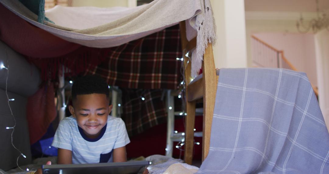 young boy playing with tablet in cozy indoor blanket fort - Free Images, Stock Photos and Pictures on Pikwizard.com