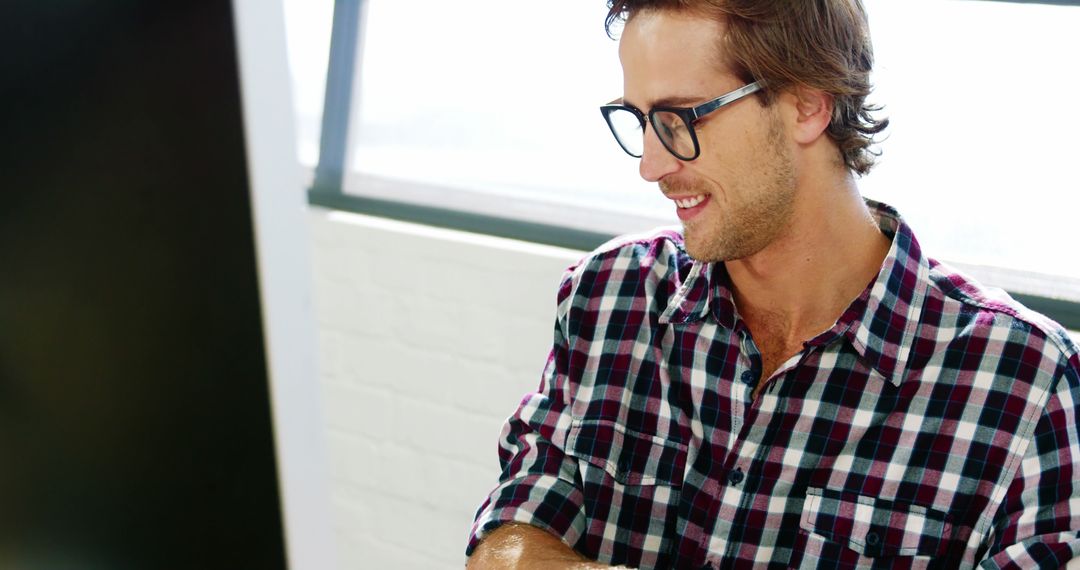 Smiling Man Wearing Plaid Shirt and Glasses Working in Office - Free Images, Stock Photos and Pictures on Pikwizard.com