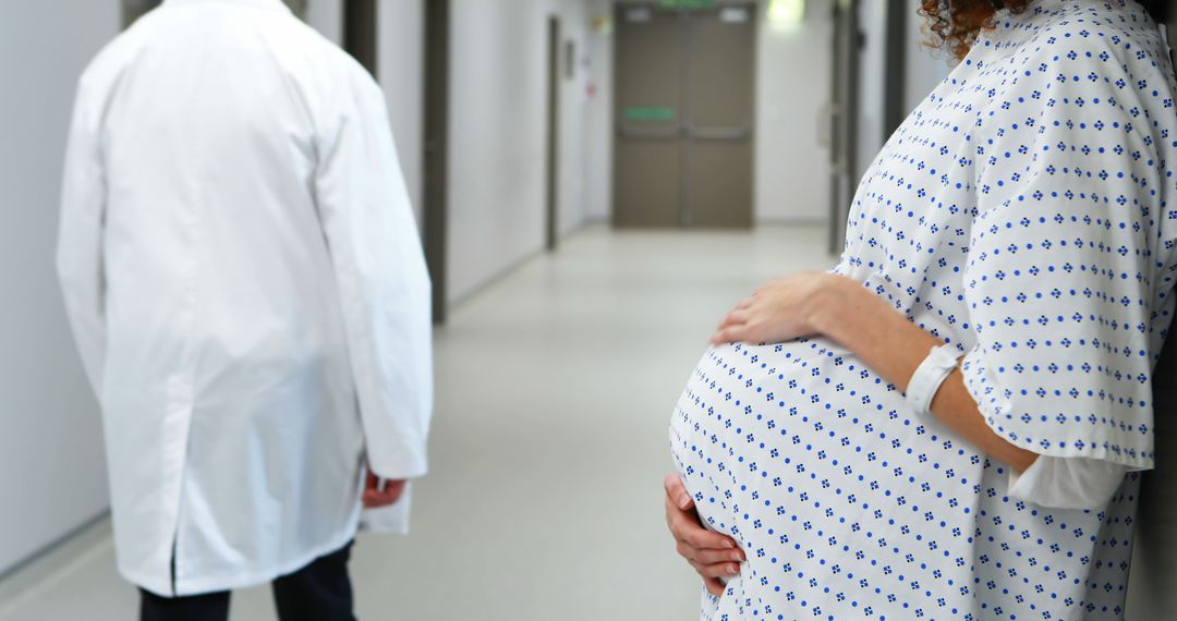 Pregnant Woman in Hospital Corridor Facing Healthcare Professional - Free Images, Stock Photos and Pictures on Pikwizard.com