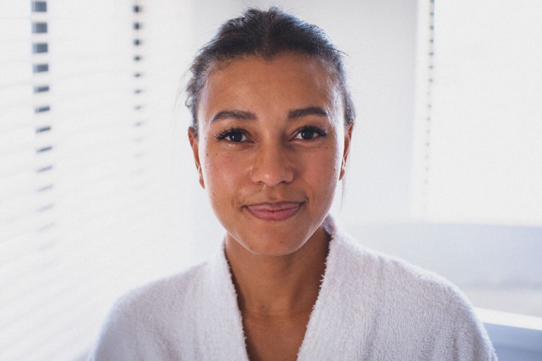 Portrait of biracial woman wearing bathrobe looking to camera and smiling - Free Images, Stock Photos and Pictures on Pikwizard.com