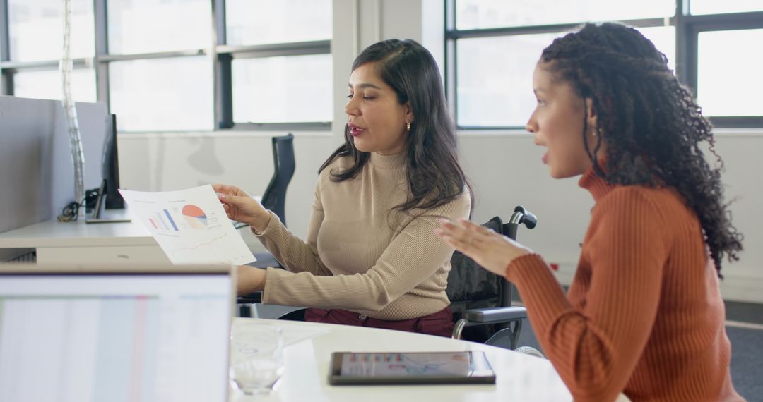 Inclusive workplace meeting showing colleagues discussing charts with wheelchair nearby