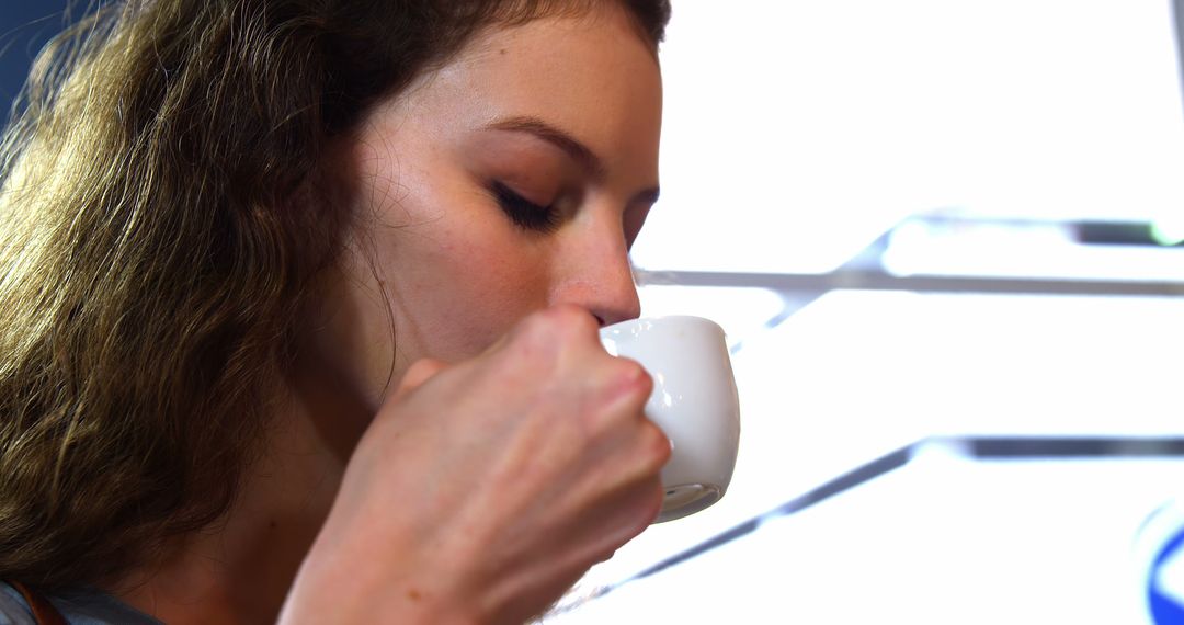 Young Woman Sipping Coffee in Bright Cafe - Free Images, Stock Photos and Pictures on Pikwizard.com