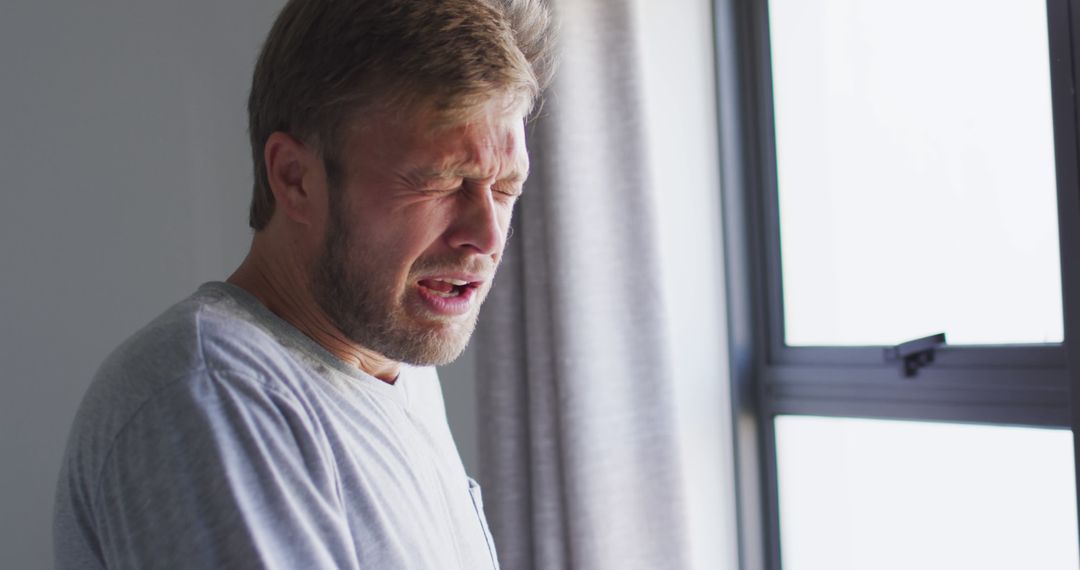 Man Sneezing Near Window at Home - Free Images, Stock Photos and Pictures on Pikwizard.com