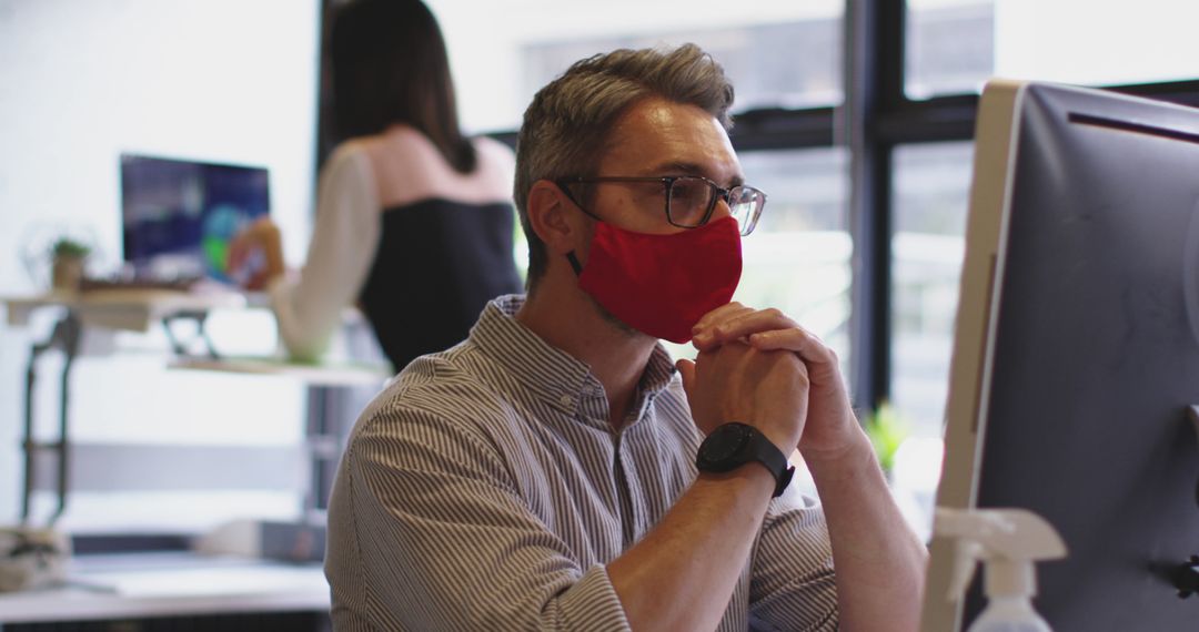 Man Working in Modern Office While Wearing a Red Face Mask - Free Images, Stock Photos and Pictures on Pikwizard.com