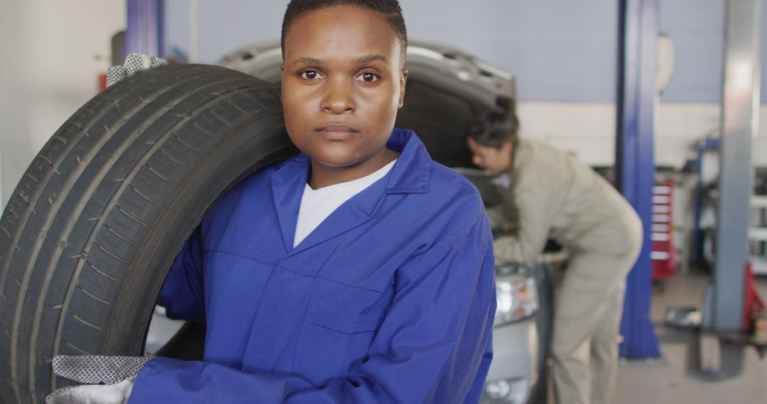 Female Mechanic Carrying Tire in Auto Repair Shop - Free Images, Stock Photos and Pictures on Pikwizard.com