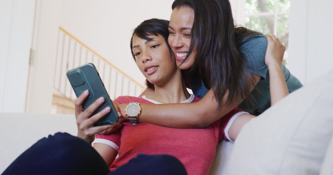 Two Women Using Smartphone and Smiling in Cozy Living Room - Free Images, Stock Photos and Pictures on Pikwizard.com