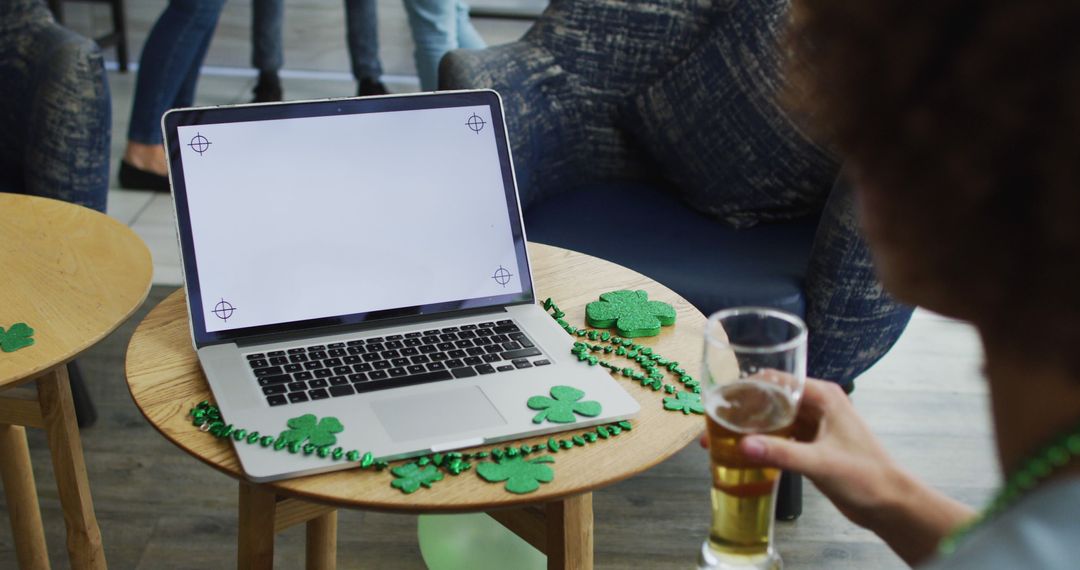 Person Celebrating St. Patrick's Day with Beer Holding Over Table with Laptop - Free Images, Stock Photos and Pictures on Pikwizard.com