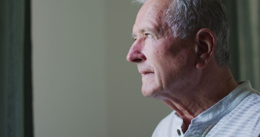 Contemplative Senior Man Gazing Out Window in Home