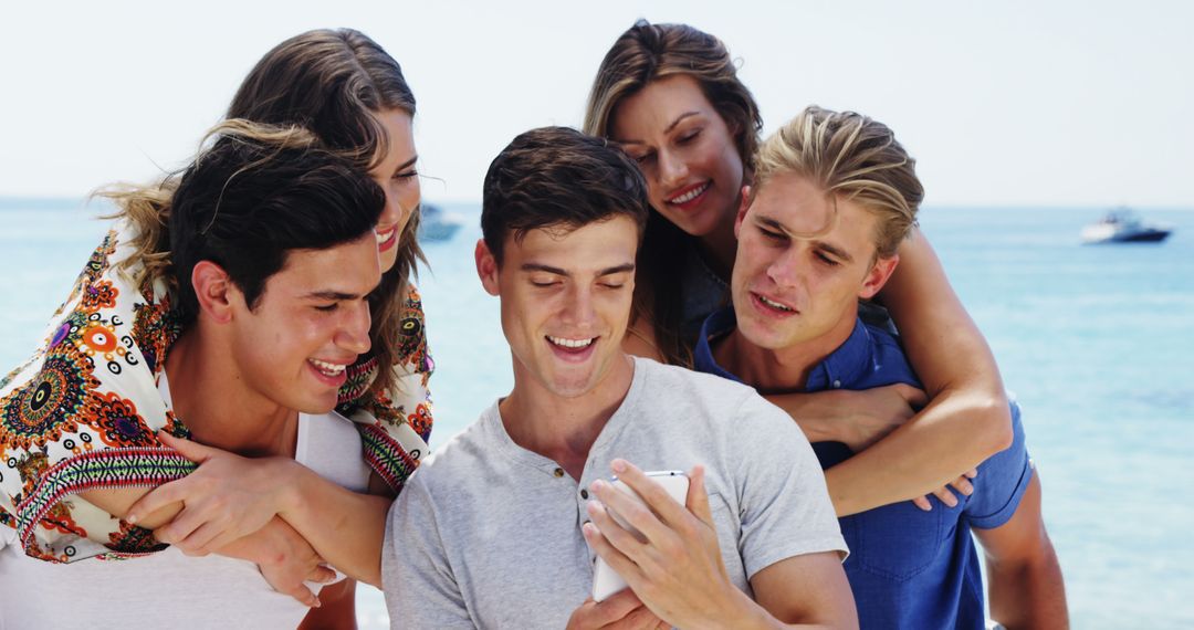Friends Laughing and Enjoying Smartphone on Sunny Beach