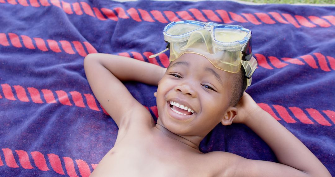 Happy Boy Relaxing on Towel with Diving Goggles - Free Images, Stock Photos and Pictures on Pikwizard.com