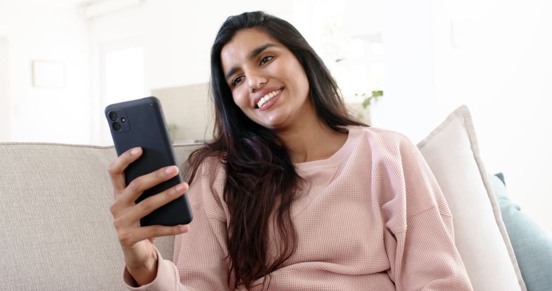 Smiling Woman Relaxed at Home Using Smartphone