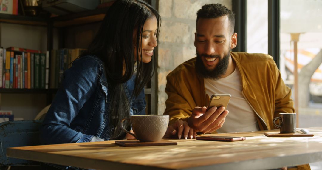 Happy Couple Enjoying Coffee and Browsing Phone in Cozy Café