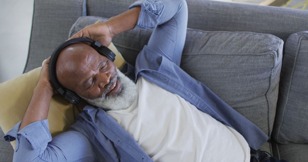 Elderly Man Relaxing Listening to Music with Headphones on Couch - Free Images, Stock Photos and Pictures on Pikwizard.com