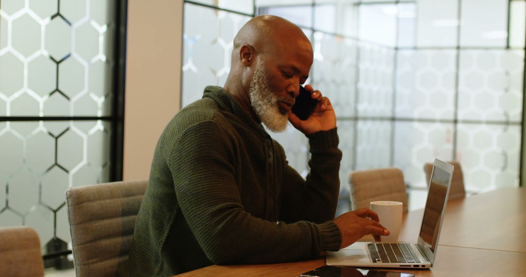 Mature Businessman Making Phone Call in Modern Office While Using Laptop - Free Images, Stock Photos and Pictures on Pikwizard.com