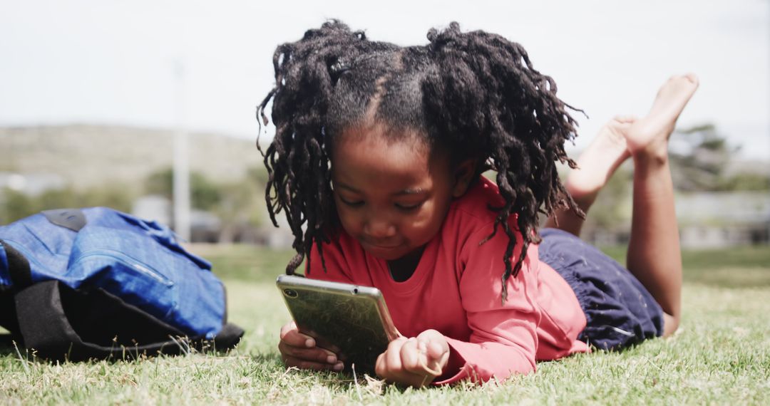 Young Girl Relaxing in Park Using Tablet