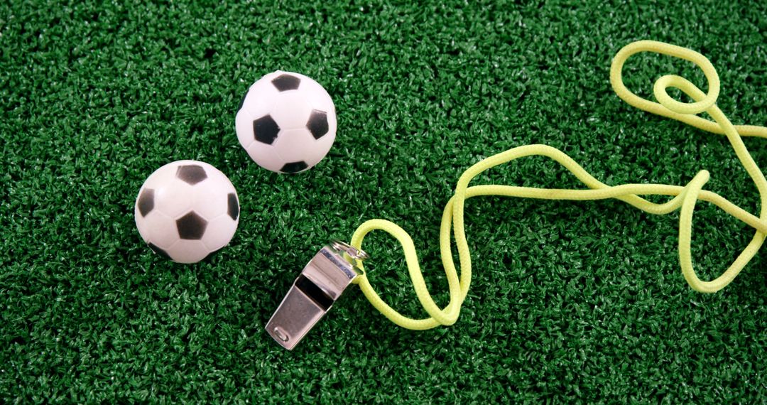Miniature Soccer Balls and Referee Whistle on Green Field