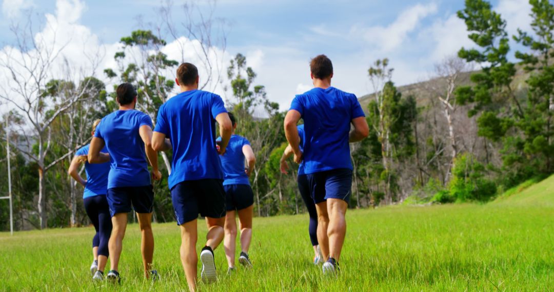 Group of young adults jogging in grassy field for fitness