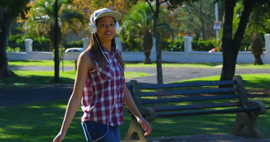 Young Woman Enjoying Walk Through Park with Headphones - Free Images, Stock Photos and Pictures on Pikwizard.com