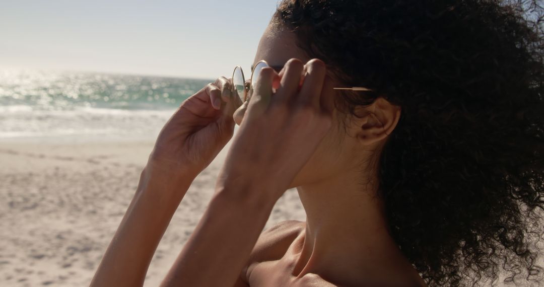 Sunset Beach Focus African American Woman Adjusting Sunglasses - Free Images, Stock Photos and Pictures on Pikwizard.com