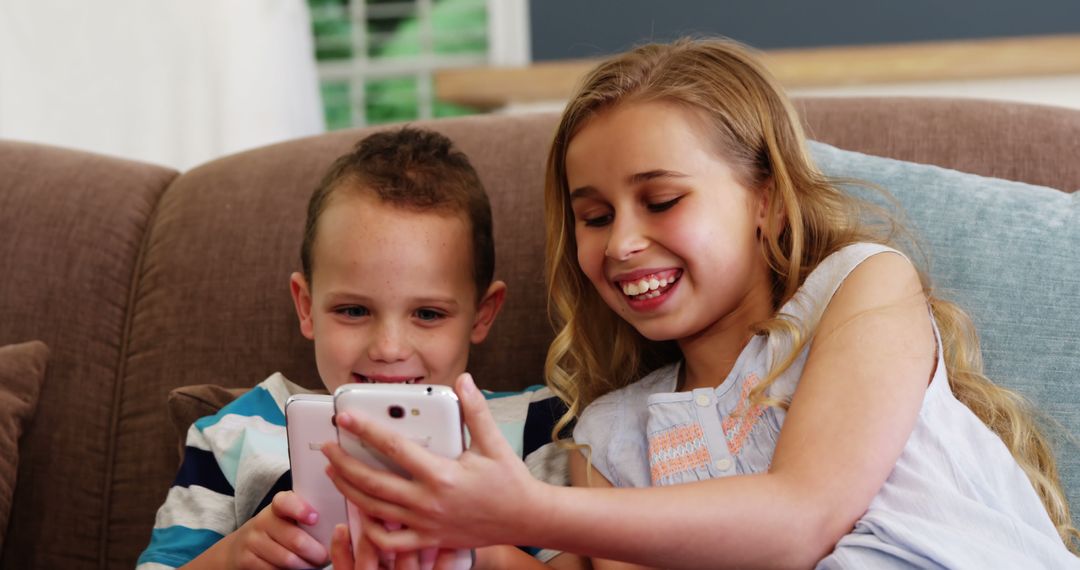 Smiling Children Using Smartphones on Couch Learning and Playing Together - Free Images, Stock Photos and Pictures on Pikwizard.com