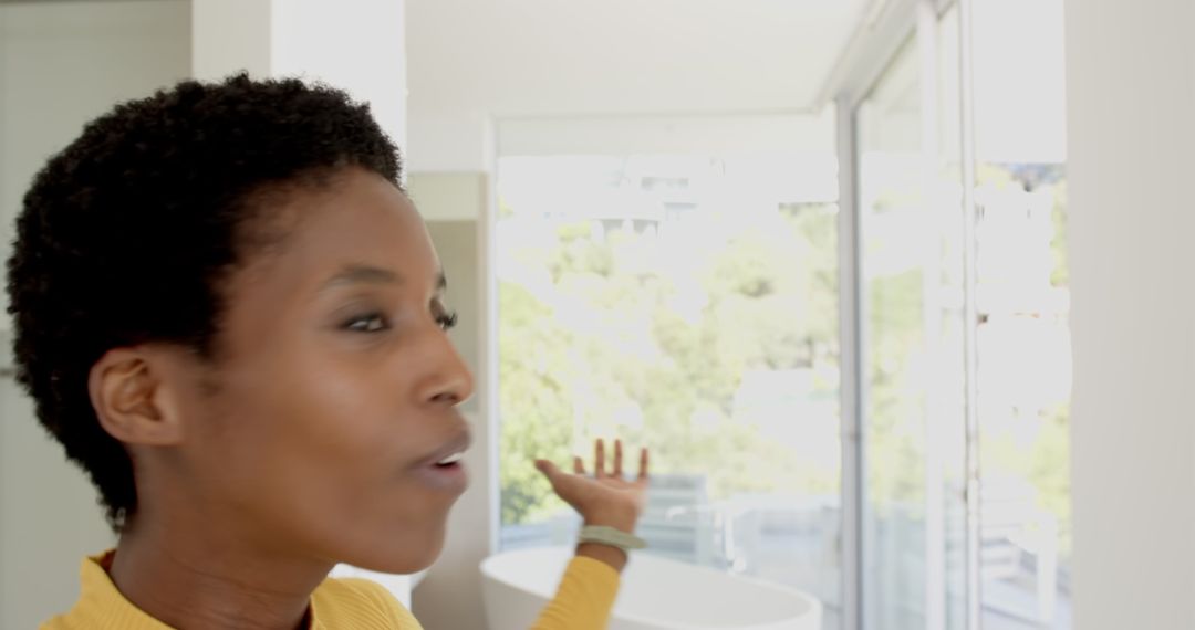Woman looking out patio door in luxurious modern bathroom