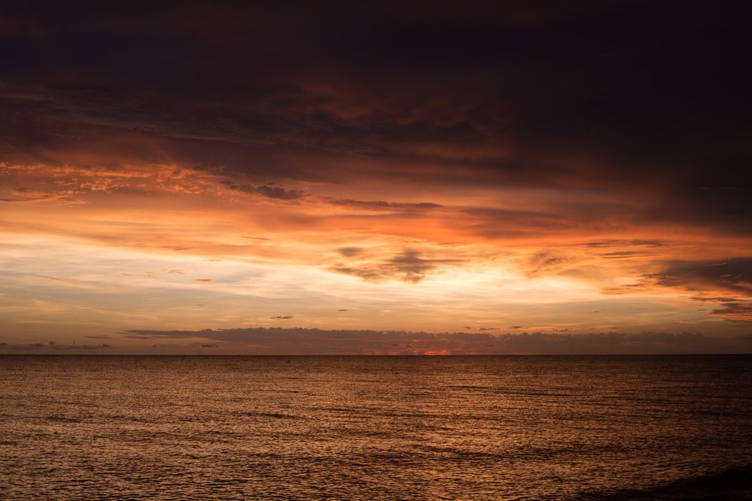 Dramatic sunset over tranquil ocean with dark clouds - Free Images, Stock Photos and Pictures on Pikwizard.com