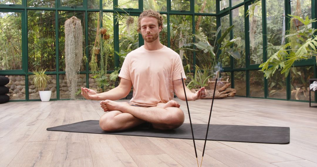 Man Practicing Meditation in Serene Glasshouse Setting