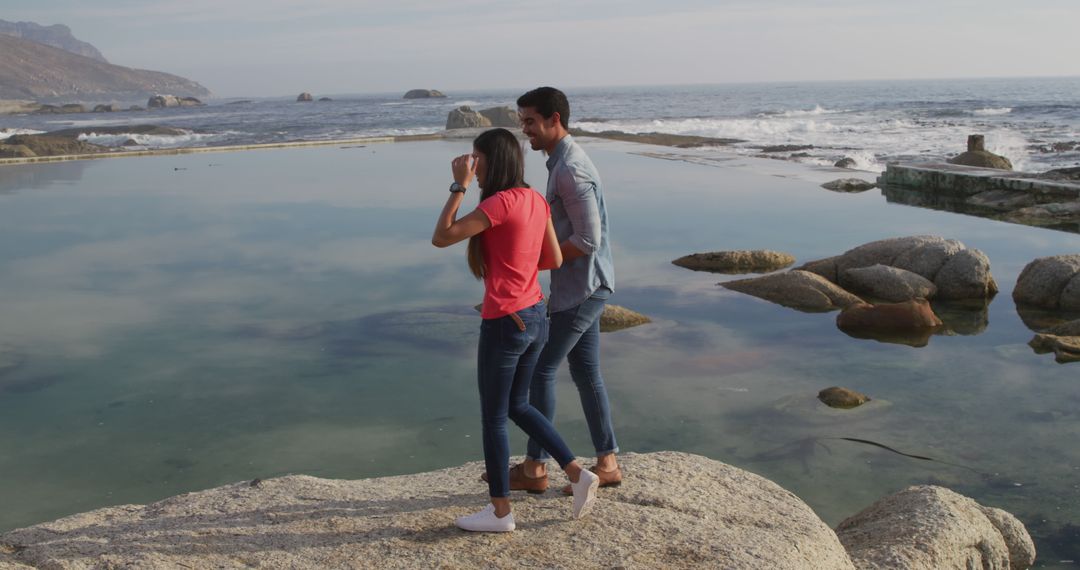 Young couple walking by scenic coastal rocks - Free Images, Stock Photos and Pictures on Pikwizard.com