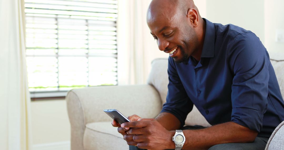 Happy Man Sitting on Couch Texting on Smartphone at Home - Free Images, Stock Photos and Pictures on Pikwizard.com